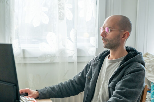 Programmer, young man in brown cable knit sweater working at computer, coding process, modern worker solving problems, specialist digital tasks, home office environment promoting productivity and calm