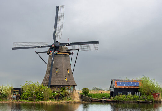 Very old traditional Dutch windmill supported by modern photovoltaic panels.
