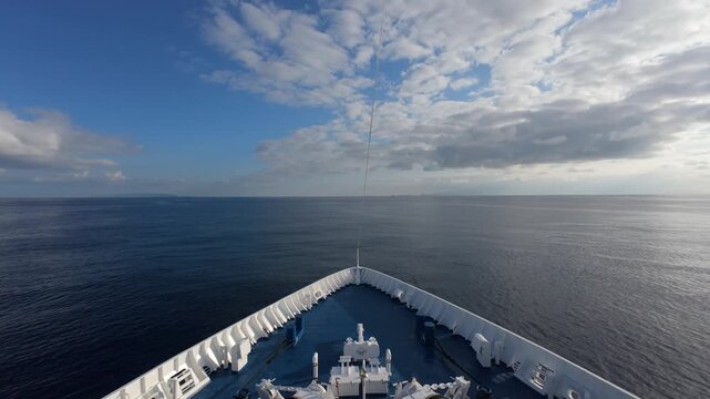 Ship bow heading into open sea with winches and calm horizon