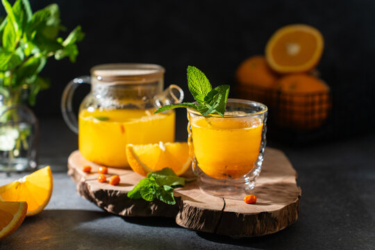 Sea buckthorn tea with orange and ginger served in glass on wooden board for wellness blogs or culinary articles, immune-boosting tea, sbiten menu, recipe