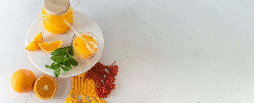 Orange sbiten banner. warming sea buckthorn juice with honey dripper, orange and mint garnish on marble tray, food photography, culinary magazines, lifestyle blogs, beverage advertisements. Copy space