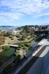 Naklejka premium 池泉回遊式日本庭園に広がる水辺と緑の美しい風景 Scenic pond-strolling Japanese garden with bridges and manicured greenery