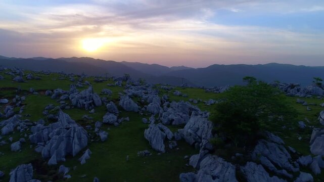 四国カルスト姫鶴牧場の石灰岩群と笠取山方向の山並みと夕日