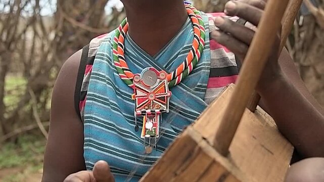 Detail shot of a native Maasai musician performing music on an authentic cultural instrument outdoors