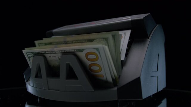 Hand removing dollars while money counter runs