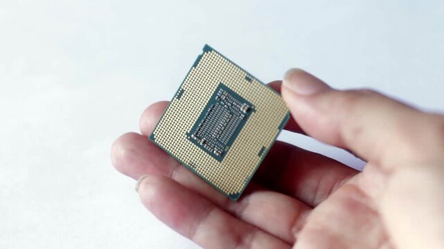 Close up of a hand holding a modern computer CPU processor chip against a white background. Concept for hardware technology, PC building, and digital processing.