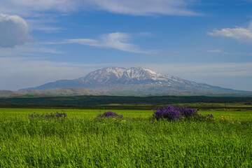 Obraz premium Image of Mount Suphan nestled among agricultural lands, against a cloudy blue sky.