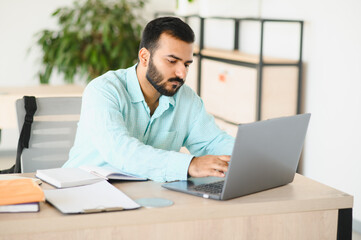 Fototapeta premium Indian student working on laptop, learning in office