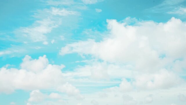Sky time-lapse photography showing rapid movement of white clouds across a bright blue sky. The dynamic motion captures changing weather patterns and the natural flow of the atmosphere, creating a vis