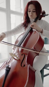 Classical music playing stringed classical musical instruments, Female cellist practicing solo piece. Closeup view of violoncello and hands of musician,A female cellist plays the cello. Vertical video