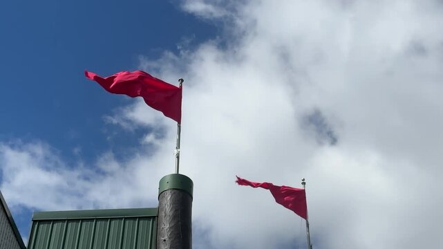 Red flags flying in the wind against a blue sky with moving clouds