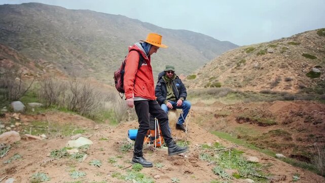 two hikers resting on hillside and smoking cigarettes during break, showing fatigue, unhealthy habit and contrast between active lifestyle and addiction in nature. Hikers smoking cigarettes
