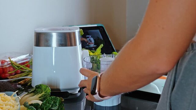 Woman placing raw Gallus gallus domesticus chicken breast pieces into white electric food processor, modern kitchen setting, preparing fresh minced poultry for healthy meal preparation., slow motion