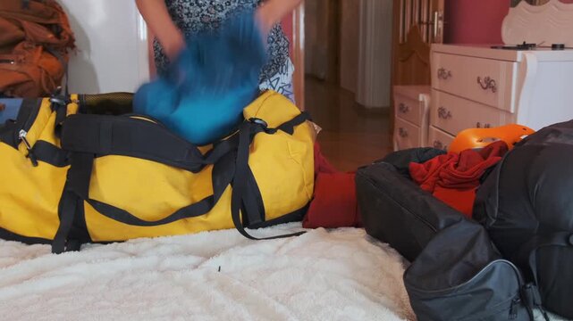 woman packing duffel bag with climbing equipment at home, organizing gear for outdoor expedition, preparing travel items and mountaineering supplies for adventure and hiking trip