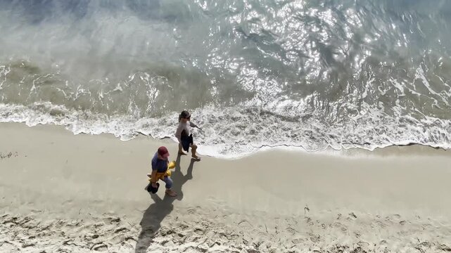 Paseo por la arena de la playa con olas, arena y espuma en verano visto desde arriba en perspectiva a&eacute;rea