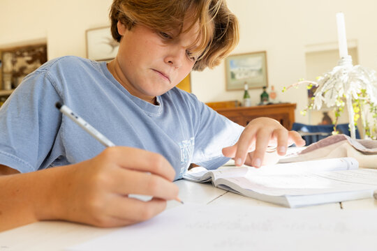12 year old boy doing homework at kitchen table