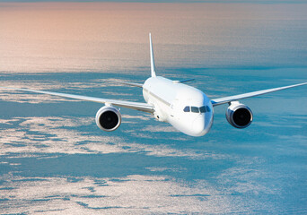Fototapeta premium Airplane flying over tropical sea at sunset
