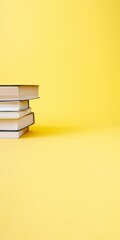 Fototapeta premium Low stack of books positioned left on bright yellow background