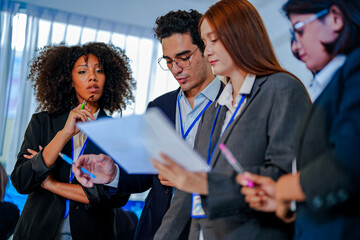 Focused African American businesswoman holding glasses and taking notes. Multiethnic group collaborating around a table in a modern corporate agency
