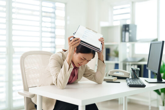 Asian adult woman overwhelmed work pressure documents deadlines struggle immense workload modern office bright workplace environment