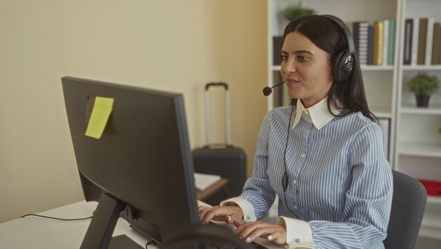 Woman hands typing on keyboard wearing headset at desk in office building, smiling at monitor; friendly support.