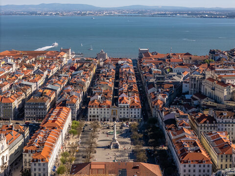 Aerial view of Rossio Square and the historic Baixa district with red-tiled rooftops leading to the Tagus River in Lisbon, Lisbon, Portugal.