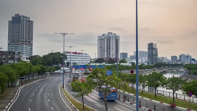 Motion blur of traffic on Vo Van Kiet Street at sunset with Ho Chi Minh City skyline and Tau Hu canal in the background.