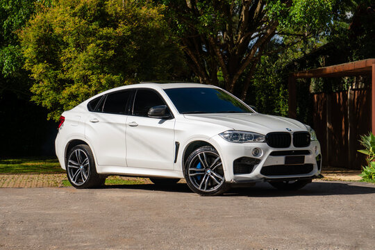White BMW X6 M front view outdoors near green trees and nature, Luxury SUV three quarters angle