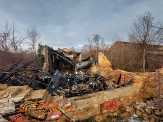 Fototapeta premium Abandoned burned building ruins with brick walls and collapsed structure