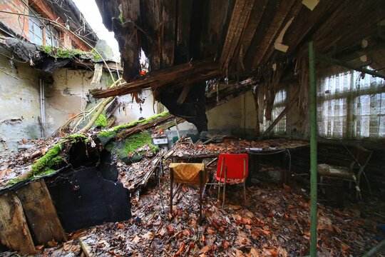 Abandoned interior with collapsed roof debris and scattered furniture