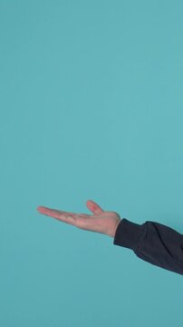 Person presenting empty space with open palm on turquoise background