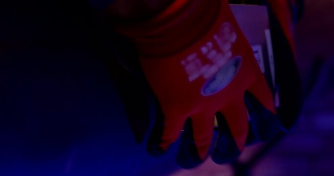 Gloved hand holding a metal ultrasonic sensor against a large industrial pipe for non-destructive testing