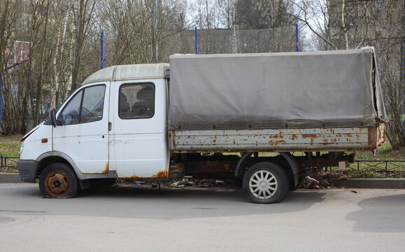 An old rusty double-cab truck is parked near a lawn, Dybenko Street, Saint Petersburg, Russia, April 12, 2026: 