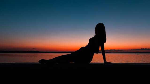 Romantic irl silhouette with the lake and beautiful sunset background