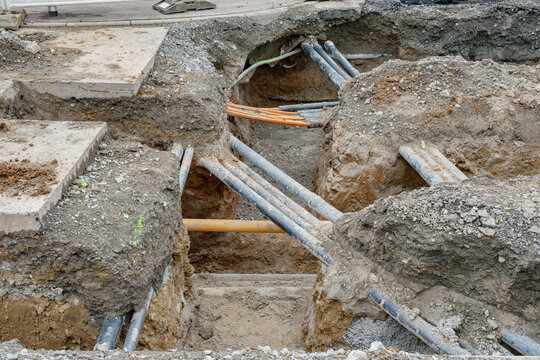 Graben f&uuml;r eine neue Fernw&auml;rmeleitung mit vielen freigelegten Erdkabeln im Kreuzungsbereich