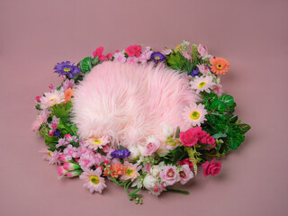 Perspective view newborn digital backdrop of a vibrant floral nest. Pink and purple flowers surround a fluffy pink fur cushion on a clean mauve studio floor. © Munif Rifa'i