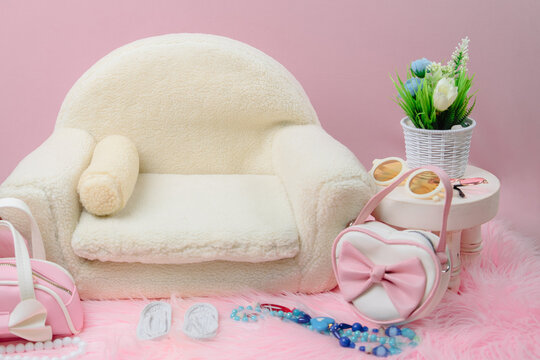 Stylish newborn digital backdrop with a cream sherpa sofa on pink fur. Features trendy heart-shaped purses, sunglasses, and a floral plant for a chic look.