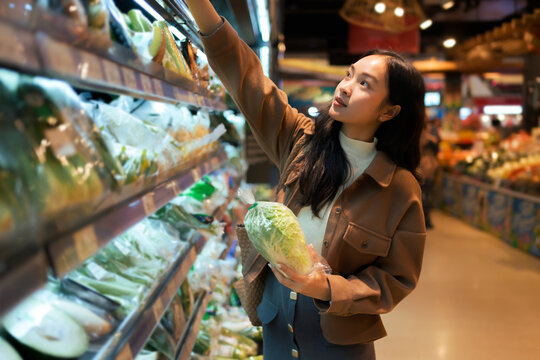 Young woman choosing healthy vegetables in a grocery store