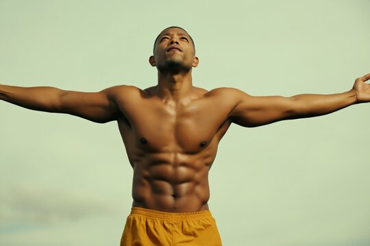 Shirtless male standing with arms outstretched outdoors