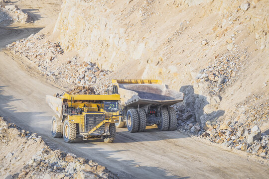 Aerial view of two large yellow haul trucks transporting rocks along a dirt road in an open-pit mine Santa Lucia de Gordon, Castile and Leon, Spain.