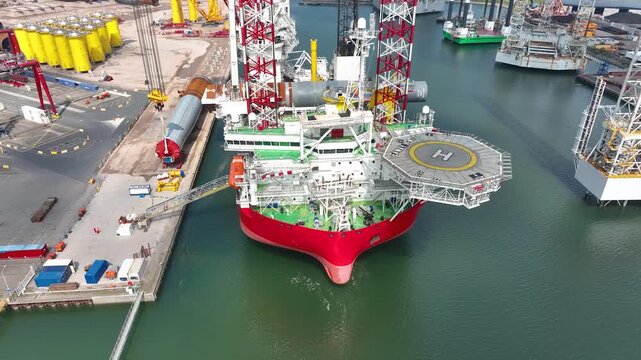 Rotterdam, Netherlands. Drone flight over industrial area with cargo ports, containers and a semi-submersible ship, heavy lifting crane. Machines designed for work at sea