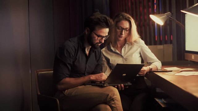 Businessman And Manager Working Together In Evening Office. Corporate Employees  Analyzing Information For Strategic Planning