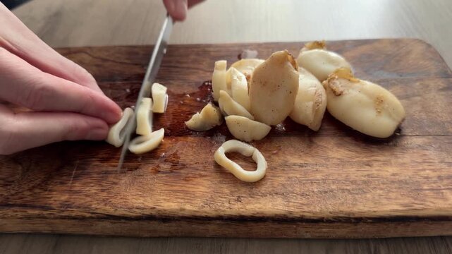 Slicing squid rings cutting board and knife tasty snack fresh gourmet food background rustic food on a table, top view copy space pescetarian diet