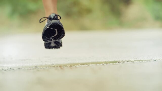 Athletic Person Running On Wet Road After Rain. Sports Workout And Active Lifestyle 