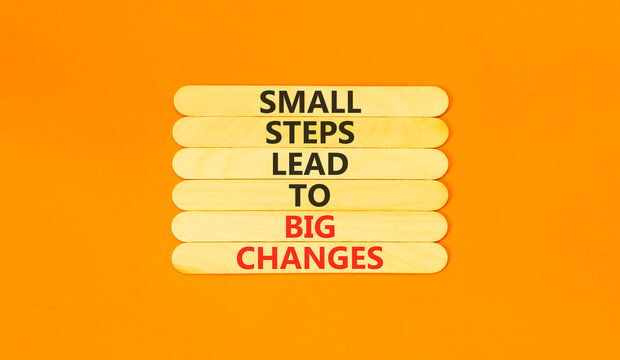 Small steps big changes words symbol. Concept words Small steps lead to big changes on beautiful wooden sticks. Beautiful orange background. Business small steps big changes concept. Copy space.