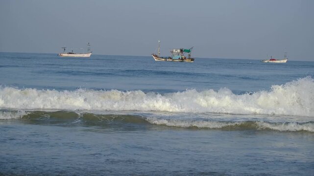 The waves at Colva beach, with a fishing trawler in the background.