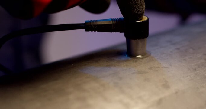 Close up of industrial ultrasonic testing sensor performing measurement on galvanized metal surface
