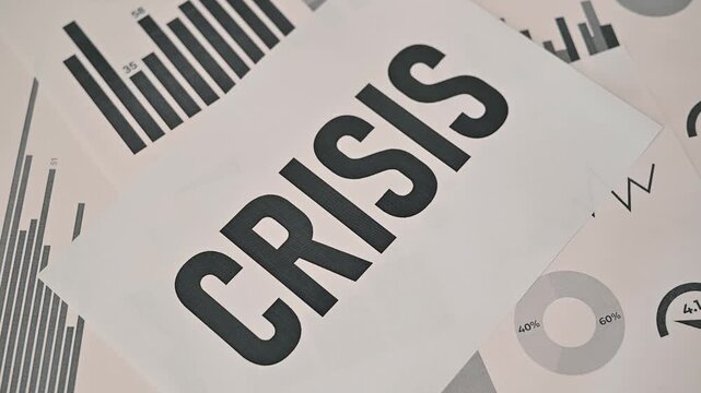 Documents on economic data are shown, highlighting various statistics and trends related to oil. The action focuses on the presentation of the word crisis, emphasizing its significance in the context