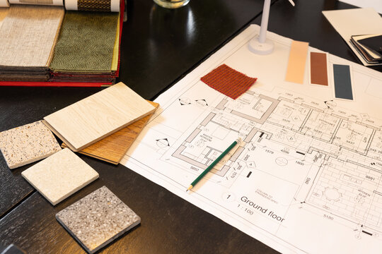 Ground plan showing green pencil and stone tiles, wood planks and fabric swatch on dark table