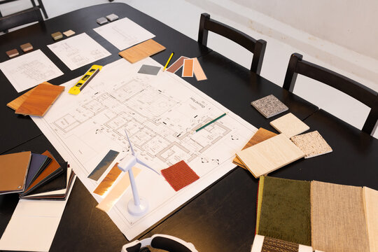 Architectural plan sitting on table in studio with veneer, pencils, spirit level and turbine model